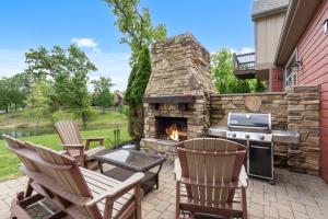 un patio avec deux chaises et une cheminée en pierre dans l'établissement Chalets Resort Luxury Lakefront Villa Family Friendly 2 Pools Free Amenities, à Lampe