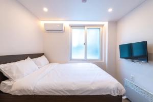 a bedroom with a white bed and a window at CrashinYongsan guest house in Seoul