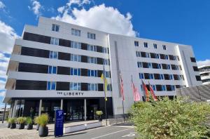 een groot wit gebouw met vlaggen ervoor bij THE LIBERTY Hotel Bremerhaven BW Signature Collection in Bremerhaven