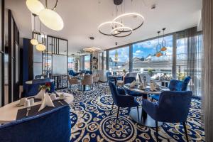 un restaurante con sillas azules, mesas y ventanas en Best Western Premier Royal Blue - Adult only, en Leipzig