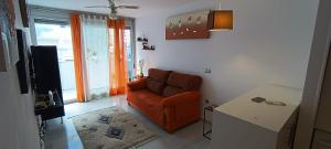 a living room with an orange chair and a table at Apartamento Elegance Benidorm in Villajoyosa