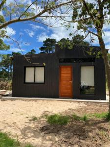 une maison noire avec une porte et des fenêtres marron dans l'établissement Casa dos cuadras de la playa, à Punta Ballena