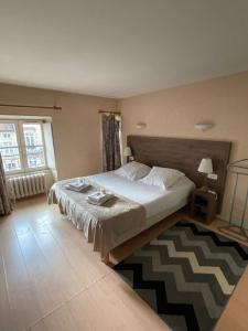 a bedroom with a large bed and a rug at Hôtel du Commerce in Semur-en-Auxois