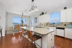 a kitchen with white cabinets and a table with chairs at Dock Holiday by Sun Palace Vacations in Fort Myers Beach