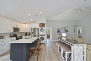 a kitchen with white cabinets and a large island with bar stools at Hidden Treasure by Sun Palace Vacations in Fort Myers Beach