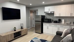 a kitchen with white cabinets and a flat screen tv at Evelyn's Manor in Winnipeg