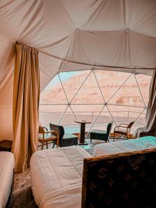 a bedroom with a tent with chairs and a table at Luxury princes camp in Wadi Rum +66 photos