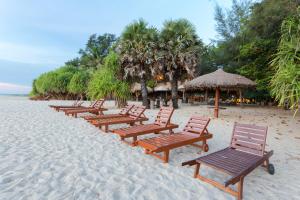 a row of wooden benches on a sandy beach at Nilaveli Beach Hotel in Nilaveli