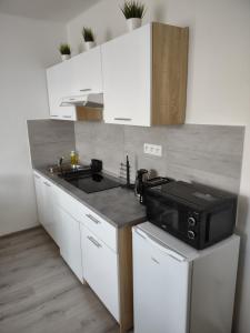cocina con armarios blancos y microondas negro en Útulný byt v centru Kroměříže, en Kroměříž 2 fotos más