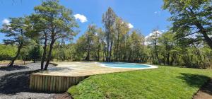 a pool in the middle of a yard with trees at Cabañas Borde Rio Las Trancas in Nevados de Chillan