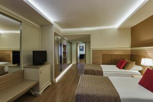 a hotel room with two beds and a flat screen tv at Delphin Deluxe Resort in Okurcalar