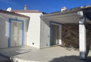 ein weißes Gebäude mit einer Tür und einer Steinmauer in der Unterkunft Villa Bambi in Budoni