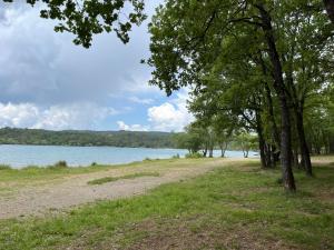 a dirt road next to a lake with trees at Charmante maison avec piscine in Artignosc-sur-Verdon