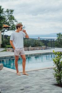 a man standing next to a swimming pool at Villa Green Garden - Infinity Pool, Jacuzzi, Sauna and Panoramic Sea View in Hreljin +69 photos