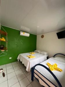 two beds in a room with green walls at Cabinas Golfito in Golfito +11 photos