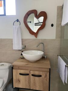a bathroom with a sink and a heart shaped mirror at Ribs coffee rock glamping in Circasia