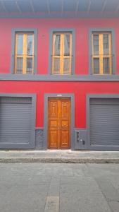 a red building with two garages and a wooden door at Apartaestudio comodo y central S2 - WiFi in Pasto