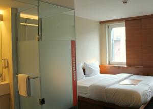 a hotel room with a bed and a shower at easyHotel Frankfurt City Center in Frankfurt