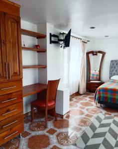a bedroom with a desk and a bed and a chair at Cabaña Rural BlueHousePaipa in Paipa