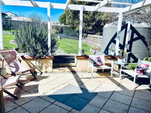 a patio with chairs and a white pergola at Updated Cottage on Large Sunny Block - 5 mins-CBD in Canadian
