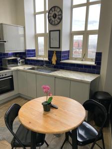 a kitchen with a wooden table and a clock on the wall at Doncaster Penthouse Long Stays in Doncaster