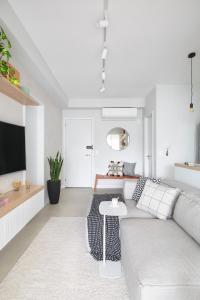 a white living room with a couch and a tv at Hotel cabana in Magalhães Bastos