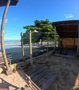 a fence on the beach with the ocean in the background at Guaecá Hostel - Cumuruxatiba in Cumuruxatiba