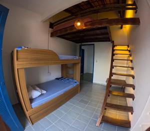 a bunk bed in a room with a ladder at Guaecá Hostel - Cumuruxatiba in Cumuruxatiba