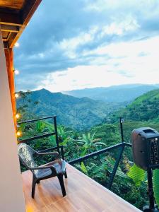 a chair on a balcony with a view of the mountains at Cabaña La Victoria in Sasaima