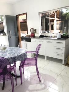 a kitchen with a table and two purple chairs at Casa Donna Flor 2 Quartos Completa Centrinho com Garagem Coberta in Catas Altas