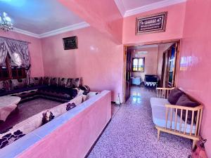 a living room with pink walls and a large couch at Maison Face au lion in Tafraout