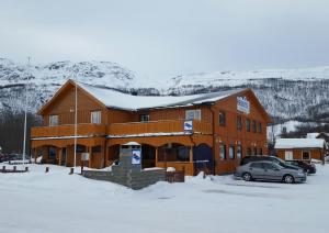 a large wooden building with a car parked in the snow at Henriksen Gjestestue in Sørkjosen