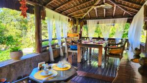 a room with a table and chairs on a porch at Pousada Lacosta in Ilhabela