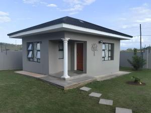 a small white house with a grass yard at Elegant guest house in Matsapha