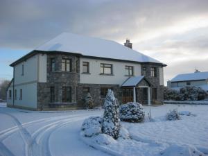 Una gran casa blanca con nieve en el suelo en Alverna House B&B, en Athlone