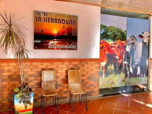 a lobby with two chairs and a poster on the wall at Hotel La Herradura in Puerto López