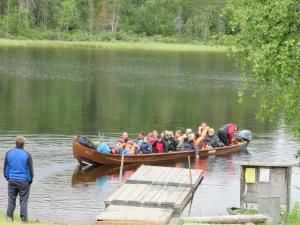 Lemmenjoen Lumo - Nature Experience & Accommodation في Lemmenjoki: مجموعة من الناس في قارب على البحيرة