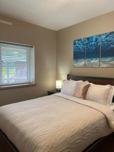 a bedroom with a large bed with three paintings on the wall at The Moorage - Luxury 2 bed & 2 bath Condo on Marina in Ucluelet