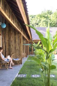 a woman sitting on a chair on the porch of a building at Pool House Studios in Kuta Lombok
