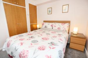 66D South Snowdon Wharf في بورثمادوج: غرفة نوم مع سرير مع زهور وردية عليه