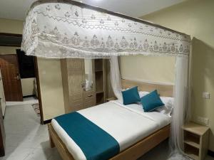 a bedroom with a canopy bed with blue pillows at Oltotoi Suites in Nairobi