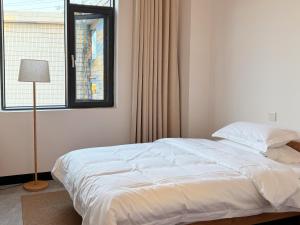 a white bed in a bedroom with a window at Bed& in Mangshi