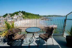 uma varanda com uma mesa e cadeiras e uma praia em The Watermark em Looe