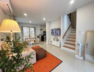a living room with a couch and a staircase at Baan Trin(บ้านตฤณ) in Chiang Rai