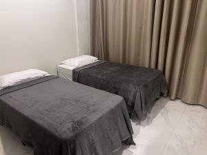 two beds sitting in a room with curtains at Apto no Centro de Miguel Pereira in Miguel Pereira