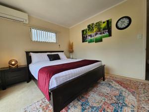 a bedroom with a bed and a clock on the wall at Bright & Cozy Studio - Private Access & Full Privacy in Auckland