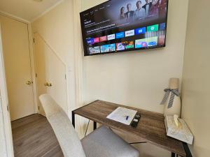 a room with a table with chairs and a flat screen tv at Bright & Cozy Studio - Private Access & Full Privacy in Auckland