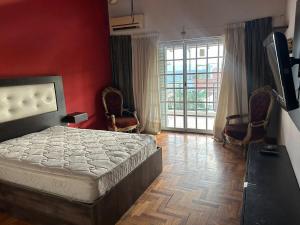 a bedroom with a bed and chairs and a television at Spacious 3BDR house in Chivilcoy with swimming pool and view in Chivilcoy +25 photos