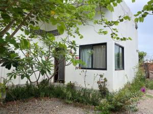 Una casa blanca con una ventana y algunas plantas. en Light-Filled 2 Bedroom Home with Private Suite, en Phumĭ Réach Born (2)