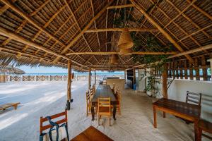 una sala da pranzo con tavolo e sedie sulla spiaggia di Zaraya Beach Jambiani a Jambiani